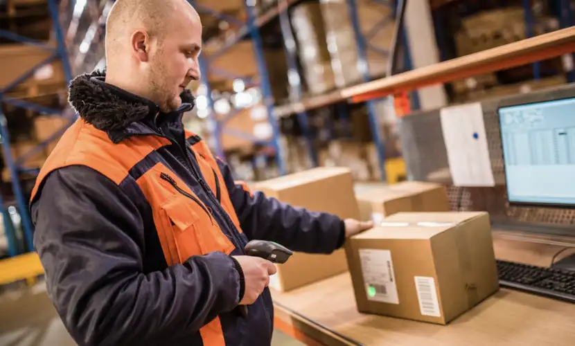 Operario en un almacén eCommerce escanea el código de barras de un producto.